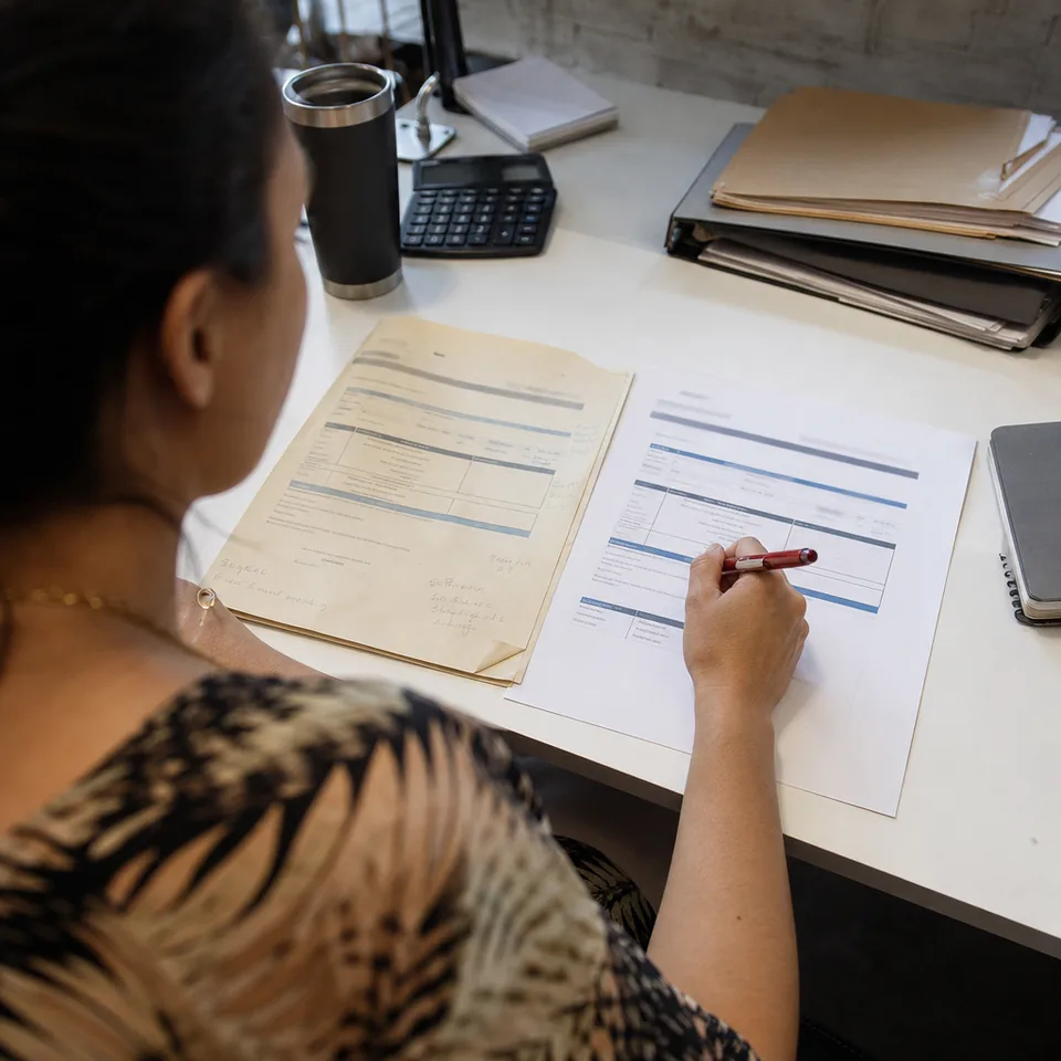 Last year's proposal and a new renewal proposal side by side on a desk with a hand holding a red pen
