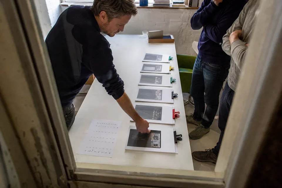 A sales lead laying out several printed client proposals in a row to review their status