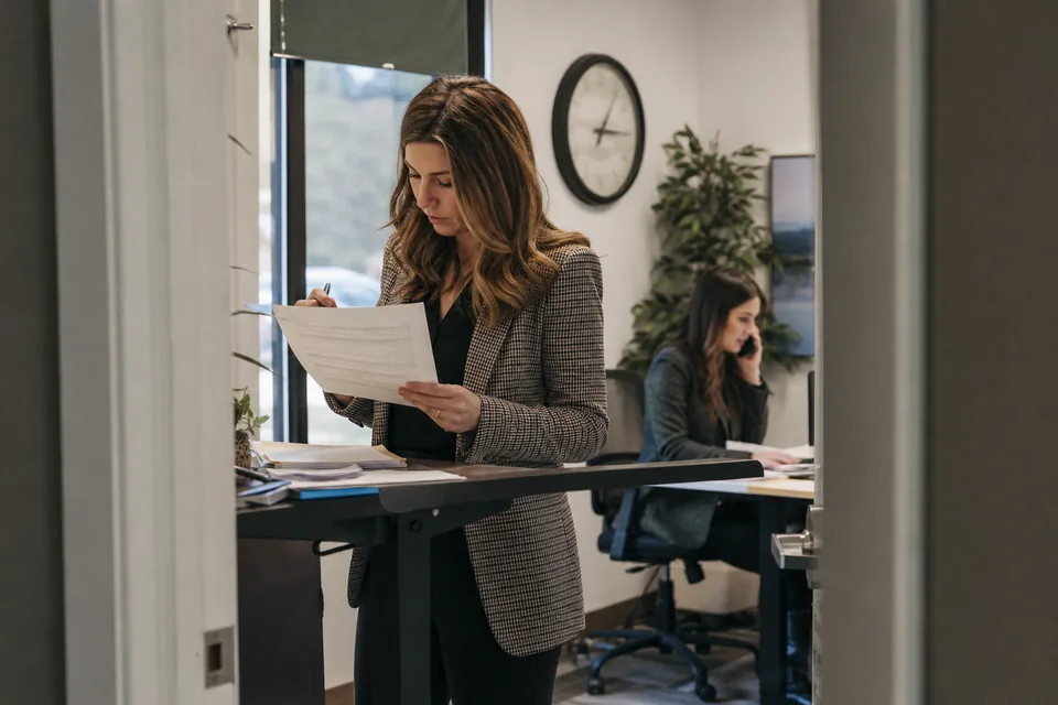 An account executive reviewing a printed order form with plan tiers at a standing desk